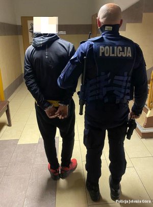 policjant prowadzi zatrzymanego mężczyznę