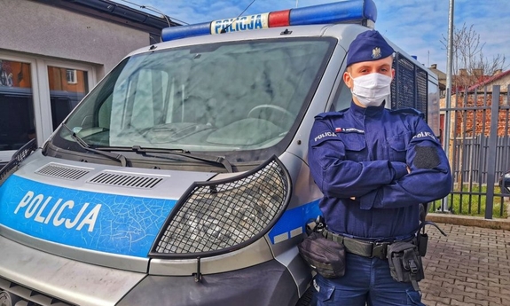 policjant stoi przy radiowozie