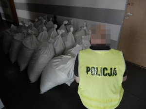 Policjant kuca przy workach z tytoniem