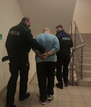 dwaj policjanci prowadzą zatrzymanego mężczyznę