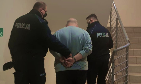 dwaj policjanci prowadzą zatrzymanego mężczyznę