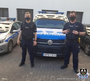 patrol Policji w kamizelkach stojący koło busa