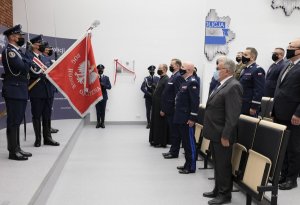 mężczyźni  w mundurach i po cywilnemu stoją na przeciwko pocztu sztandarowego