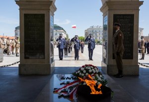 umundurowani policjanci oddają hołd przed pomnikiem Nieznanego Żołnierza, na pierwszym planie wieńce