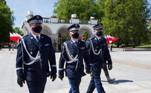 trzej umundurowani policjanci maszerują, w tle Nieznanego Żołnierza