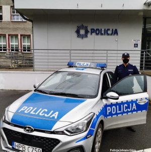 policjant stoi przy radiowozie