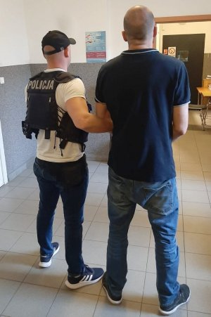 policjant prowadzi zatrzymanego