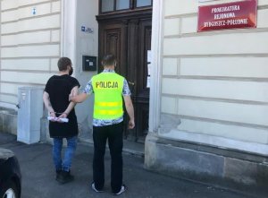 Policjant wraz z zatrzymanym przed wejściem do prokuratury