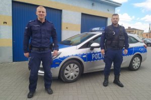 dwaj policjanci stoją przy radiowozie