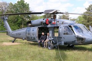 młody mężczyzna i pilot siedza na skraju policyjnego śmigłowca