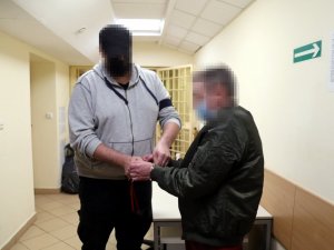 policjant zakłada kajdanki zatrzymanemu mężczyźnie