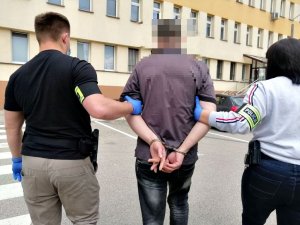 &quot;Policjanci prowadzą mężczyznę skutego kajdankami&quot;&gt;