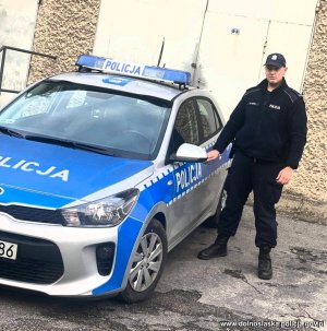 policjant stojący koło radiowozu