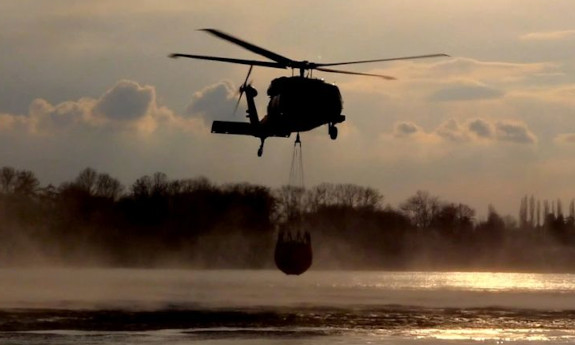 Policyjny helikopter nad zbiornikiem wodnym z podwieszonym Bambi Bucket.