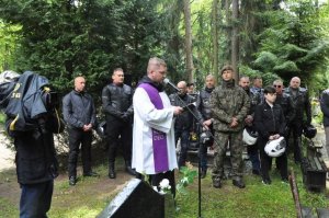 uczestnicy rajdu na cmentarzu, na środku stoi ksiądz przy mikrofonie