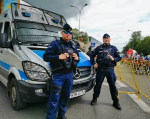 dwóch umundurowanych policjantów z Oddziału Prewencji Policji w Białymstoku, którzy stoją przed radiowozem