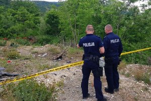 Dwaj polscy policjanci stoją przy żółtej taśmie wydzielającej miejsce zdarzenia.