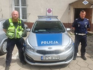 dwaj policjanci stoją przy radiowozie