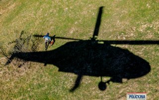 Cień rzucany przez przez helikopter, obok biegnący ratownik GOPR.