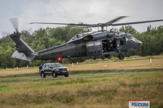 Policyjny Black Hawk wznosi się w powietrze z zatrzymanym i kontrterrorystami, w tle samochód.