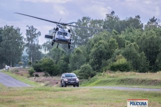 Policyjny Black Hawk nad szybko jadącym  samochodem typu SUV.