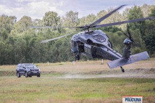 Policyjny Black Hawk widziany od tyłu nisko nad drogą którą nadjeżdża samochód typu SUV.