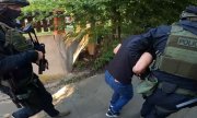 dwaj umundurowani policjanci prowadzą zatrzymanego