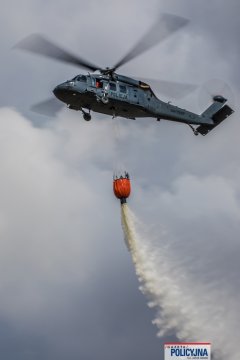 Policyjny śmigłowiec zrzucający wodę z Bambi Bucket.