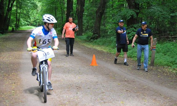 uczestnik zawodów rowerowych Olimpiad Specjalnych na rowerze i trzej organizatorzy