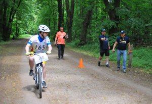 uczestnik zawodów rowerowych Olimpiad Specjalnych na rowerze i trzej organizatorzy