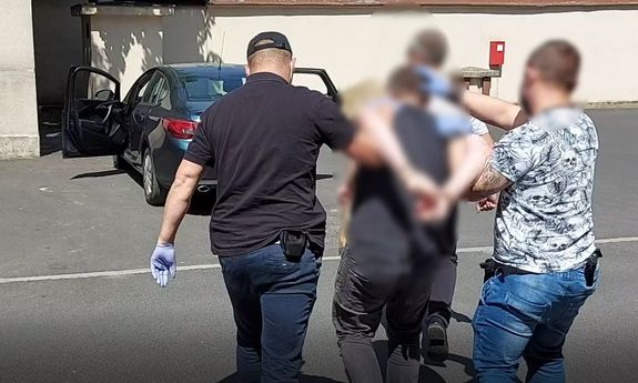 policjanci ubrani po cywilnemu prowadzą zatrzymanego