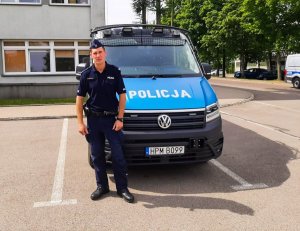 policjant stoi przed radiowozem