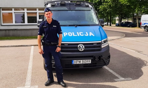 policjant stoi przed radiowozem