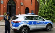 policjantka stoi przy radiowozie zaparkowanym przy kościele