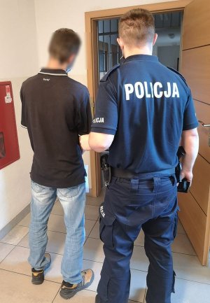 policjant z zatrzymanym przed drzwiami policyjnej celi