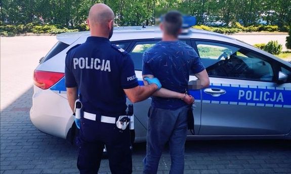 policjant prowadzi zatrzymanego do radiowozu