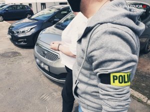 policjant prowadzi zatrzymana kobietę przez parking