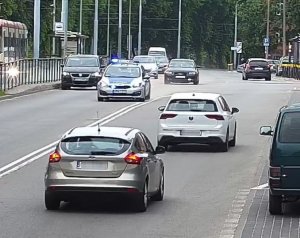 policyjny radiowóz eskortuje do szpitala auto z rodzącą kobietą