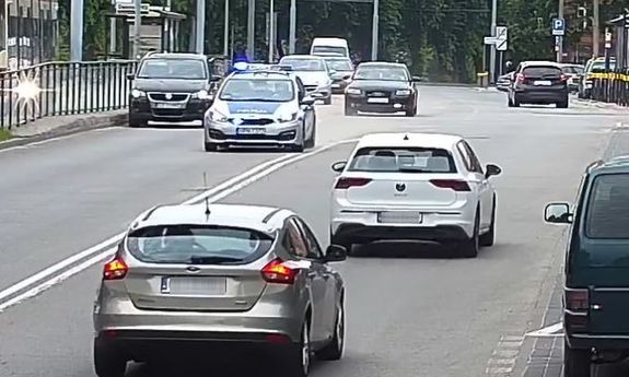 policyjny radiowóz eskortuje do szpitala auto z rodzącą kobietą