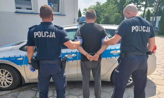 umundurowani policjanci prowadzą zatrzymanego. podejrzany o kradzież ma założone kajdanki na ręce trzymane z tyłu