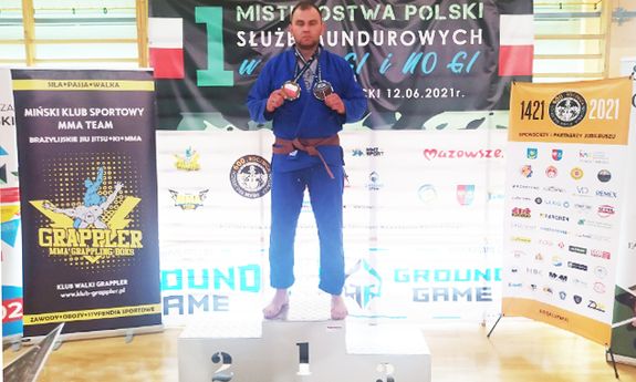 Policjant w granatowym kimono brazylijskiego jiu-jitsu na I miejscu na podium