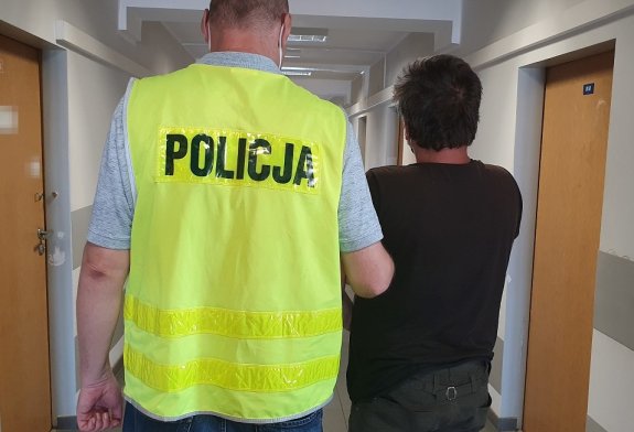 Policjant prowadzi zatrzymanego mężczyznę