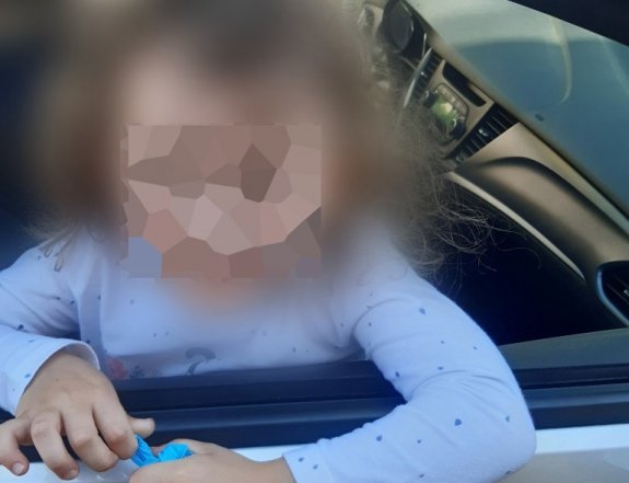 Mała dziewczynka wyglądająca przez otwarte okno radiowozu