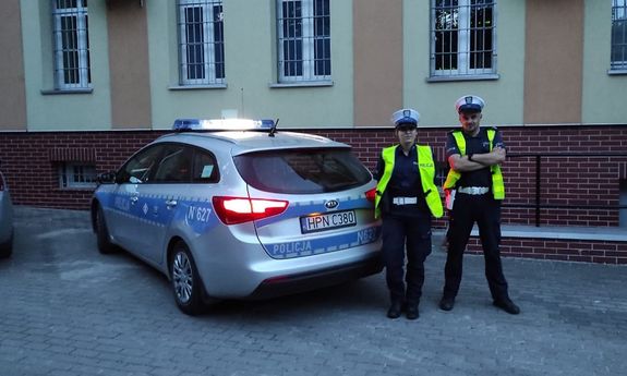 policjantka i policjant ruchu drogowego stojący przy radiowozie