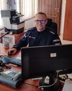 Policjant siedzący przed monitorem.