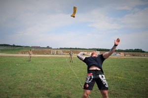 Policjant w stroju sportowym rzuca za siebie żółtym kaloszem.