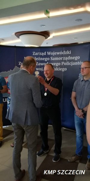 mężczyzna w stroju sportowym otrzymuje od mężczyzny w garniturze puchar