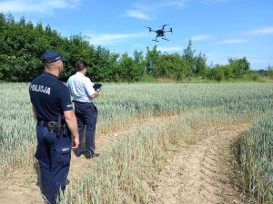 policjant i mężczyzna ubrany po cywilnemu, który steruje dronem