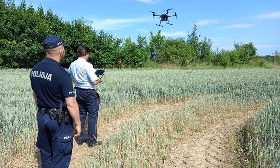 policjant i mężczyzna ubrany po cywilnemu, który steruje dronem