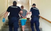 mężczyzna prowadzony po schodach przez policjantów
